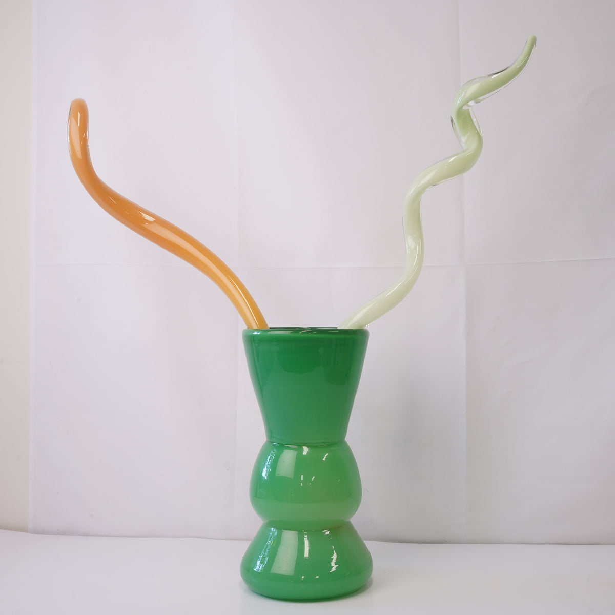 green hand-blown glass vase with sculptural handblown glass flowers and orange and green prongs, creating a bold, artistic statement piece for interiors