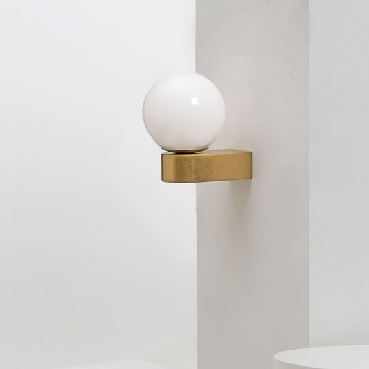 Modern wall sconce with a round hand-blown glass shade mounted on a neutral wall, creating a soft ambient glow ideal for contemporary interiors in melbourne, australia 
