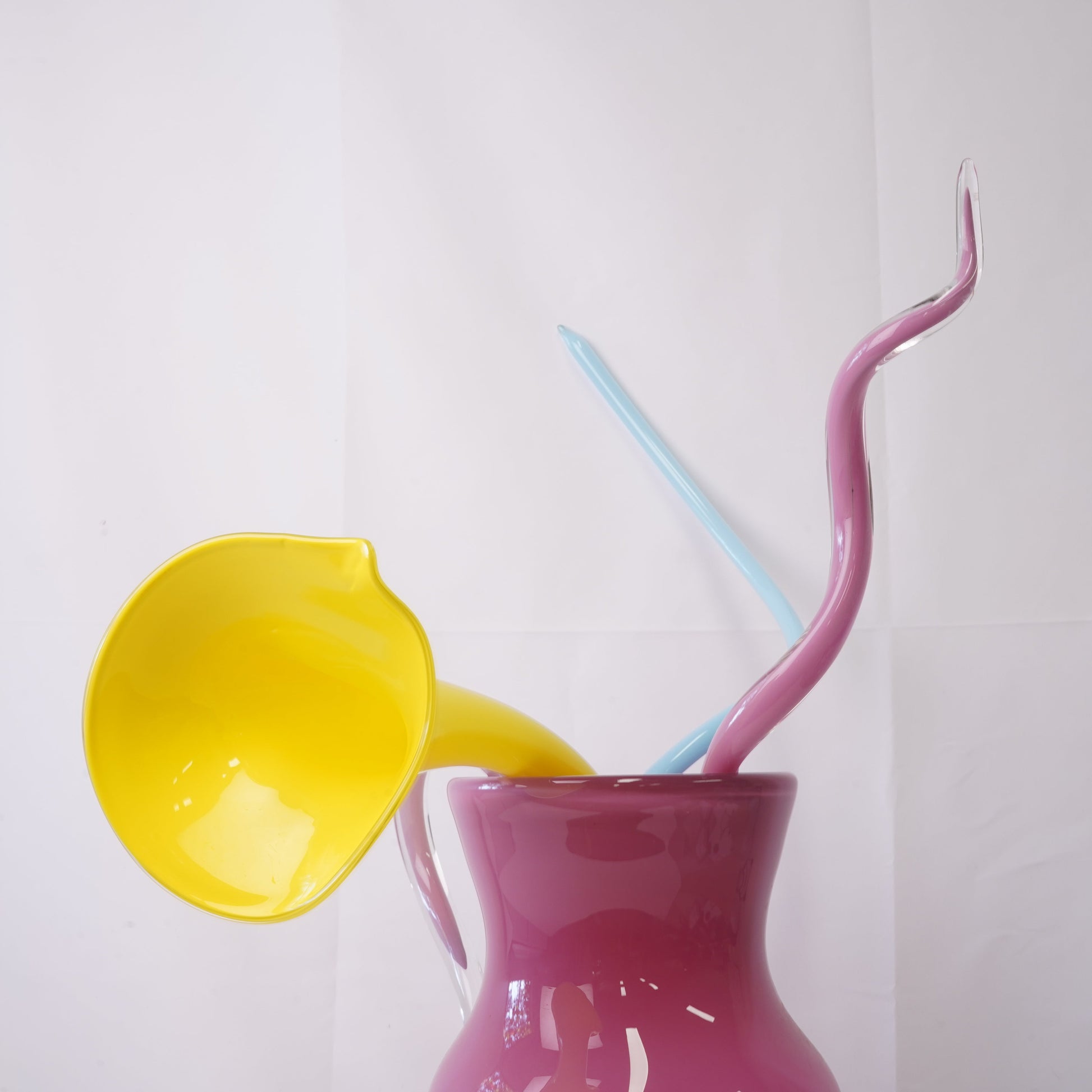 pink hand-blown glass vase with sculptural handblown glass flowers and blue  and yellow prongs, creating a bold, artistic statement piece for interiors