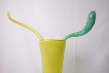 yellow hand-blown glass vase with sculptural handblown glass flowers and green prongs, creating a bold, artistic statement piece for interiors